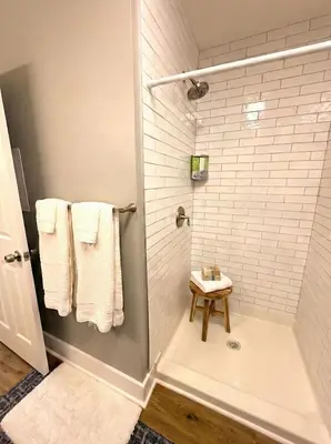 a white bathroom with a shower with towels and a stool at Cozy Walk up King Bed fast WiFi in Wilmington