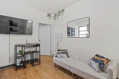 a white living room with a couch and a mirror at Heart of Downtown Manhattan - Stylish One Bedroom Apartment in Vibrant Union Square in New York