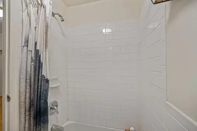 a bathroom with a shower with white tile at Heart of Downtown Manhattan - Stylish One Bedroom Apartment in Vibrant Union Square in New York
