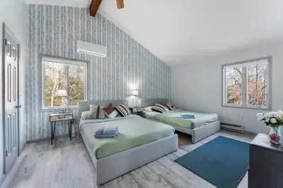 a bedroom with two beds and a couch at Gorgeous 5BD w Hot-Tub & Pool villa located in the middle of Pocono in East Stroudsburg