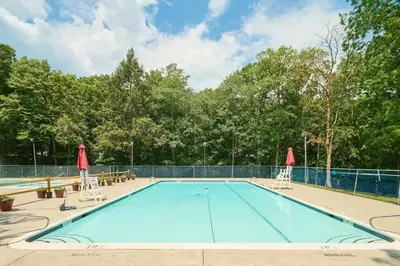 a large swimming pool with two lawn chairs at Gorgeous 5BD w Hot-Tub & Pool villa located in the middle of Pocono in East Stroudsburg
