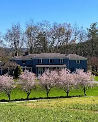 a large blue house in a field with trees at 37 Oak Ridge House in Wellsboro