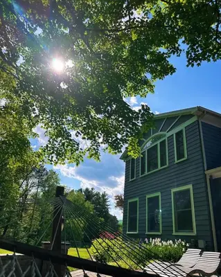 a green house with the sun shining in front of it at 37 Oak Ridge House in Wellsboro