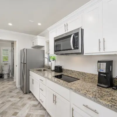 a kitchen with white cabinets and a stainless steel refrigerator at Jellystone Park Birchwood Acres in Greenfield Park