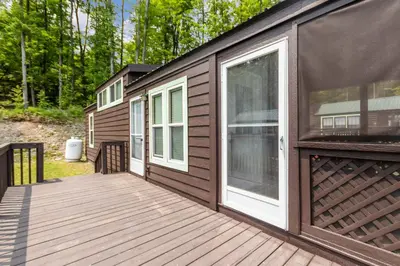 a house with a wooden deck with a door at Jellystone Park Birchwood Acres in Greenfield Park