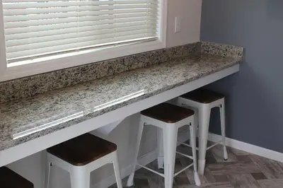 a kitchen counter with stools under a window at Jellystone Park Birchwood Acres in Greenfield Park