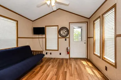 a living room with a couch and a clock on the wall at Jellystone Park Birchwood Acres in Greenfield Park