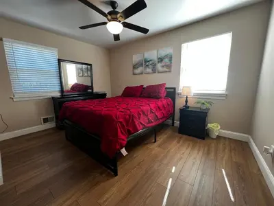 a bedroom with a bed with a red comforter and a ceiling fan at Spacious 3 BR Ewing Home -Quiet in Trenton