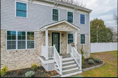 a brick house with a white staircase leading to the front door at A home away from home in Hightstown
