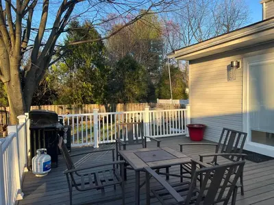 a picnic table and chairs on a deck with a fence at A home away from home in Hightstown