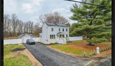 a white house with a car parked in the driveway at A home away from home in Hightstown