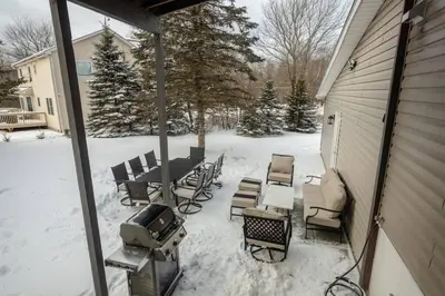 a snow covered patio with a grill and tables and chairs at Pocono Retreat Movies Games Spacious in Long Pond
