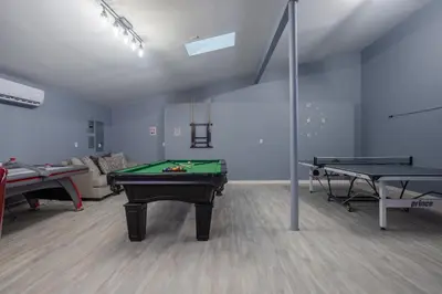 a room with two ping pong tables and a couch at Pocono Retreat Movies Games Spacious in Long Pond