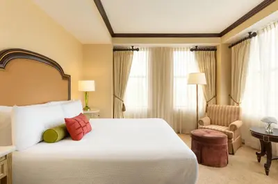 a hotel room with a large bed and a chair at Hotel Du Pont in Wilmington