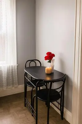 a table with two chairs and a vase with flowers on it at Spacious 4BR near NYC with Parking, 10min MetLife, 20min Times Sq in North Bergen