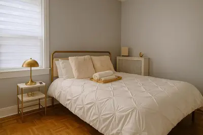 a bedroom with a white bed with a book on it at Spacious 4BR near NYC with Parking, 10min MetLife, 20min Times Sq in North Bergen