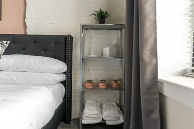 a shelf next to a bed with pillows and plants at A Luxury Urban 1BR Queen Bed-Parking - Heart of Historic Germantown - Temple & LaSalle -106- Stay Long Term! in Philadelphia