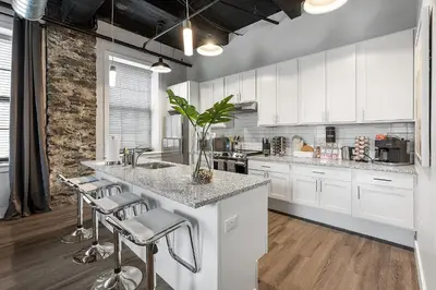 a kitchen with white cabinets and a counter with stools at A Luxury Urban 1BR Queen Bed-Parking - Heart of Historic Germantown - Temple & LaSalle -106- Stay Long Term! in Philadelphia