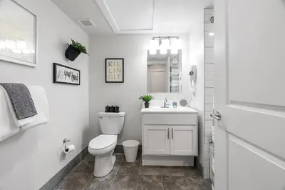 a white bathroom with a toilet and a sink at A Luxury Urban 1BR Queen Bed-Parking - Heart of Historic Germantown - Temple & LaSalle -106- Stay Long Term! in Philadelphia