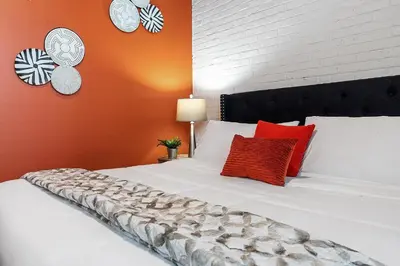 a bed with red and white pillows and clocks on the wall at Luxury Urban 1BR King Bed-Parking - Heart of Historic Germantown - Temple & LaSalle -105- Stay Long Term! in Philadelphia