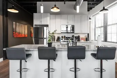a kitchen with white cabinets and a counter with stools at Luxury Urban 1BR King Bed-Parking - Heart of Historic Germantown - Temple & LaSalle -105- Stay Long Term! in Philadelphia