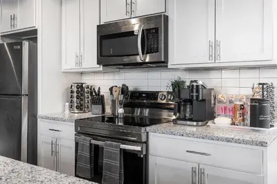 a kitchen with white cabinets and a stove and a microwave at Luxury Urban 1BR King Bed-Parking - Heart of Historic Germantown - Temple & LaSalle -105- Stay Long Term! in Philadelphia