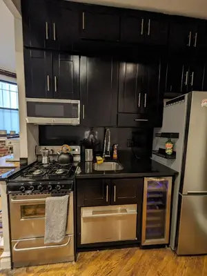 a kitchen with stainless steel appliances and black cabinets at Lovely Room at 3 bedroom Apt at the heart of East Village in New York
