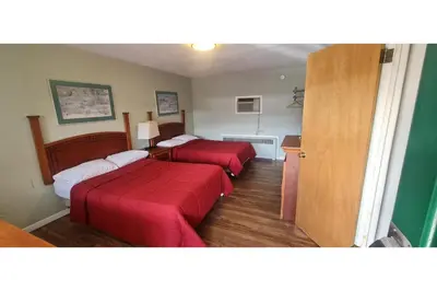 a hotel room with two beds with red sheets at Werry's Cottages Motel & Pub by OYO East Stroudsburg Poconos in East Stroudsburg