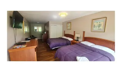 a hotel room with two beds and a flat screen tv at Werry's Cottages Motel & Pub by OYO East Stroudsburg Poconos in East Stroudsburg