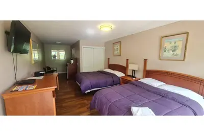 a hotel room with two beds and a television at Werry's Cottages Motel & Pub by OYO East Stroudsburg Poconos in East Stroudsburg