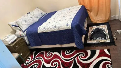 a bed with a blue and white blanket and a rug at Divine Villa and Resorts 67 Sherman 5mins to EWR Airport and 4mins to Penn Station Newark, 20Mins to New York in Newark