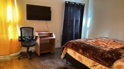 a bedroom with a bed and a chair and a television at Divine Villa and Resorts 67 Sherman 5mins to EWR Airport and 4mins to Penn Station Newark, 20Mins to New York in Newark