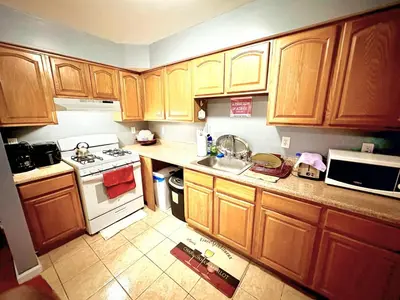 a kitchen with wooden cabinets and a white stove top oven at Room G DIVINE VILLA AND RESORT, 6 MINS TO AIRPORT, 4MINS TO PENN STATION. in Newark