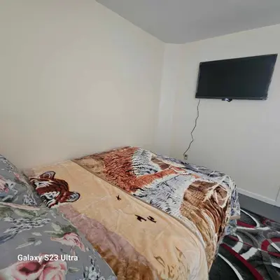 a bedroom with a bed and a flat screen tv at Room G DIVINE VILLA AND RESORT, 6 MINS TO AIRPORT, 4MINS TO PENN STATION. in Newark