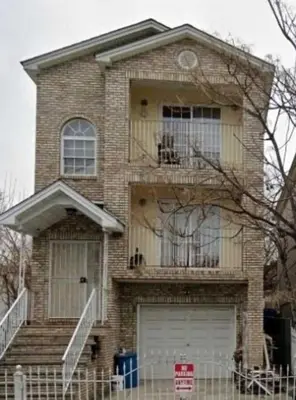 a brick house with a balcony and a garage at Room G DIVINE VILLA AND RESORT, 6 MINS TO AIRPORT, 4MINS TO PENN STATION. in Newark