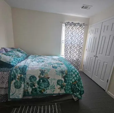 a bedroom with a bed with a comforter and a window at Room J Divine Villa and Resorts 5mins to EWR Airport and 4mins to Penn Station Newark, New York in Newark