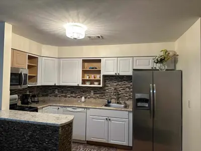 a kitchen with white cabinets and a stainless steel refrigerator at Room J Divine Villa and Resorts 5mins to EWR Airport and 4mins to Penn Station Newark, New York in Newark