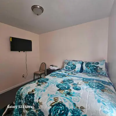 a bedroom with a bed with a blue floral bedspread at Room K Divine Villa and Resorts 5mins to EWR Airport and 4mins to Penn Station Newark, New York in Newark