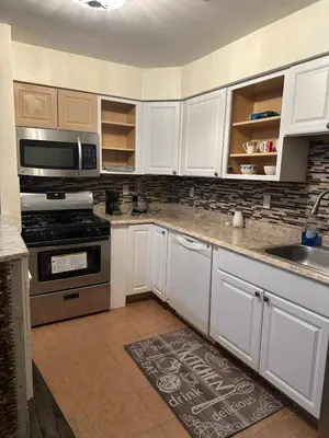 a kitchen with white cabinets and a stove top oven at Room K Divine Villa and Resorts 5mins to EWR Airport and 4mins to Penn Station Newark, New York in Newark