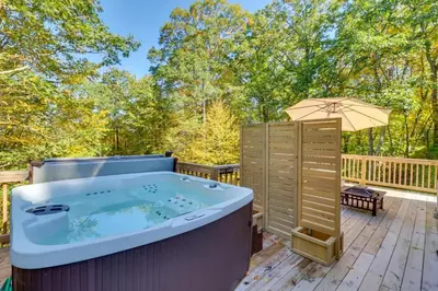 a hot tub on a deck with an umbrella at Pocono Getaway A frame Cabin w/ Hot Tub Sauna in East Stroudsburg