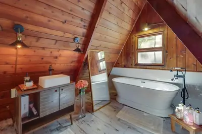 a bathroom with a tub and a sink in a wooden wall at Pocono Getaway A frame Cabin w/ Hot Tub Sauna in East Stroudsburg