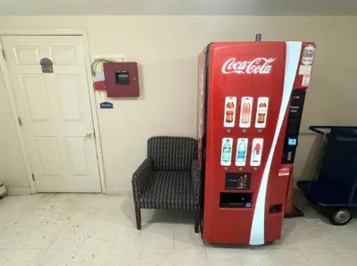 a cocacola machine with a chair next to a door at Kiteville Lancaster in Strasburg