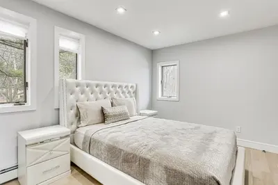 a white bedroom with a large bed and two windows at Waterfront Lake Hopatcong Home with Boat Dock! in Mount Arlington