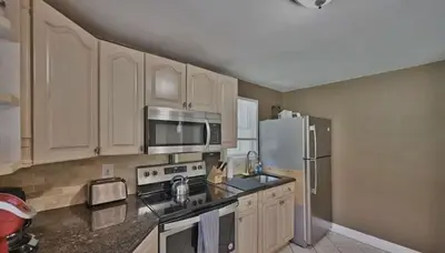 a kitchen with wooden cabinets and a stainless steel refrigerator at Hideaway - LakeHouse/spa/dock/ in Pocono Summit