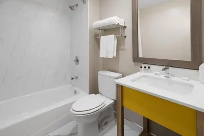 a white bathroom with a toilet and a sink at Days Inn by Wyndham Staten Island in Staten Island
