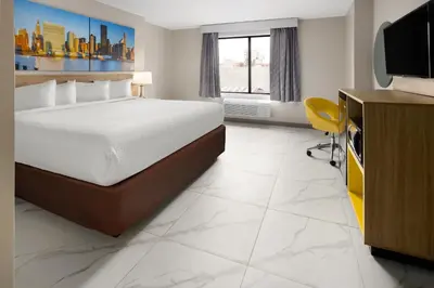 a hotel room with a bed and a flat screen tv at Days Inn by Wyndham Staten Island in Staten Island
