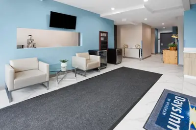 a lobby with two chairs and a tv on a wall at Days Inn by Wyndham Staten Island in Staten Island