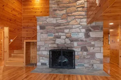 a stone fireplace in a living room with wooden floors at Fisher Mountain Retreat in Woodward