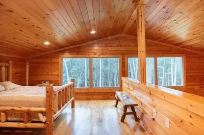 a log cabin bedroom with a bed and windows at Fisher Mountain Retreat in Woodward