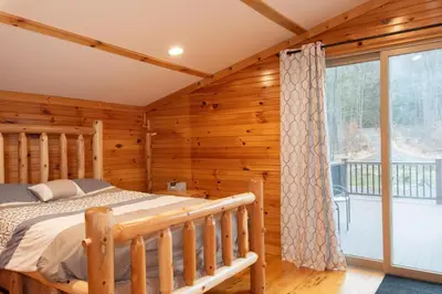 a log cabin bedroom with a bed and a large window at Fisher Mountain Retreat in Woodward